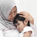 Asian muslim mother wearing hijab calming her sad and crying daughter, single mom and baby girl together