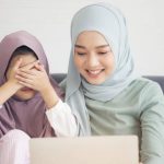 An Islamic mother rears her daughter close eye for video call online to father at home