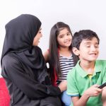 mother with her children at home sitting on sofa chair and talking with white background